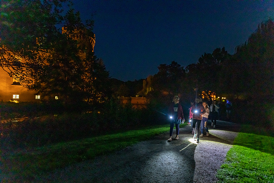 Kinder erkunden mit der Taschenlampe den Schlosspark